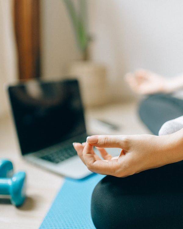 Person sitting peacefully on a mat in a softly lit room.