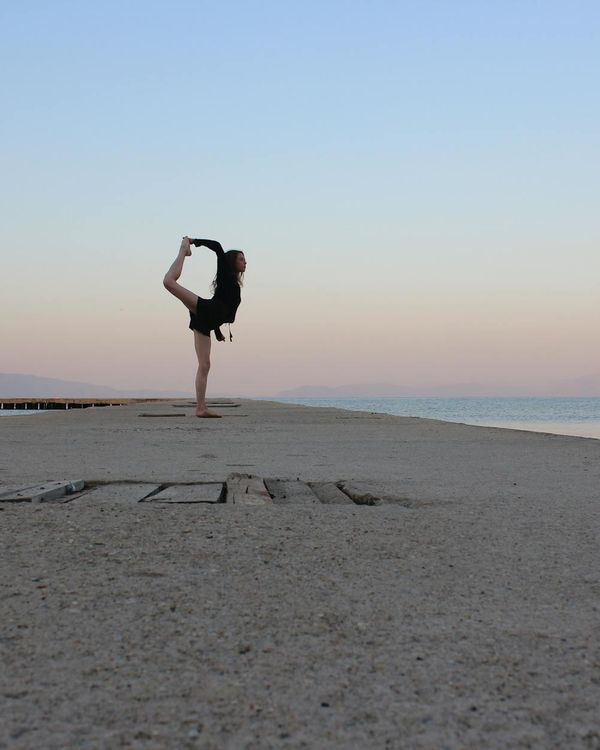 Silhouette of a person in a balancing yoga pose at sunset.